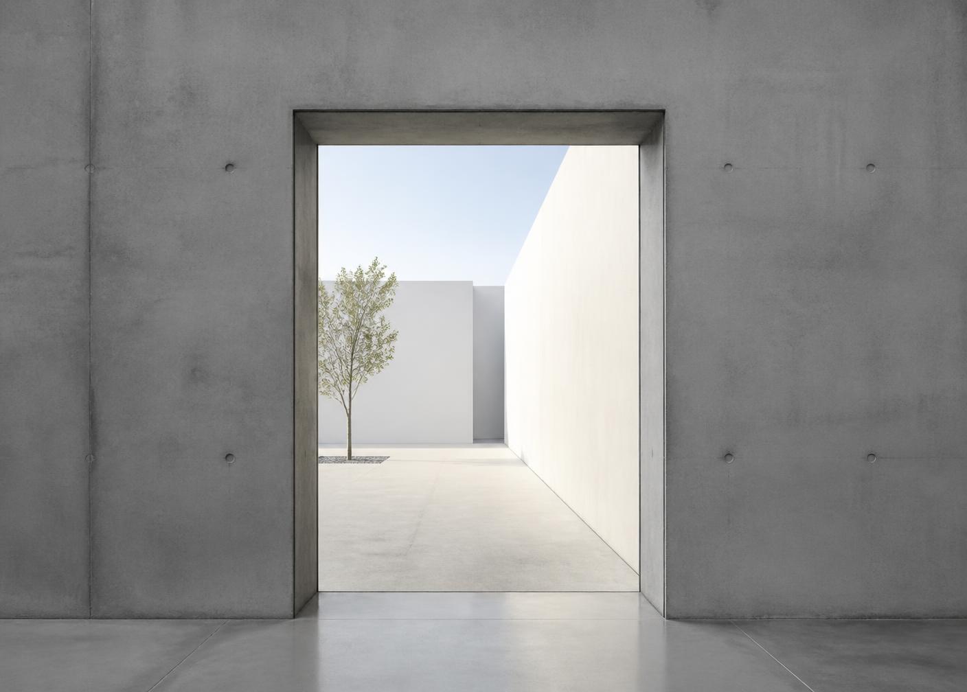 A precise opening in a thick concrete wall framing an open courtyard beyond